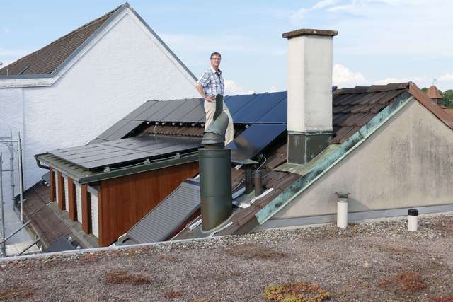 Die Solarmodule passen sich der Dachform auf beiden Seiten des Giebels an (hier mit dem Inhaber der Apotheke, Robert Joset).